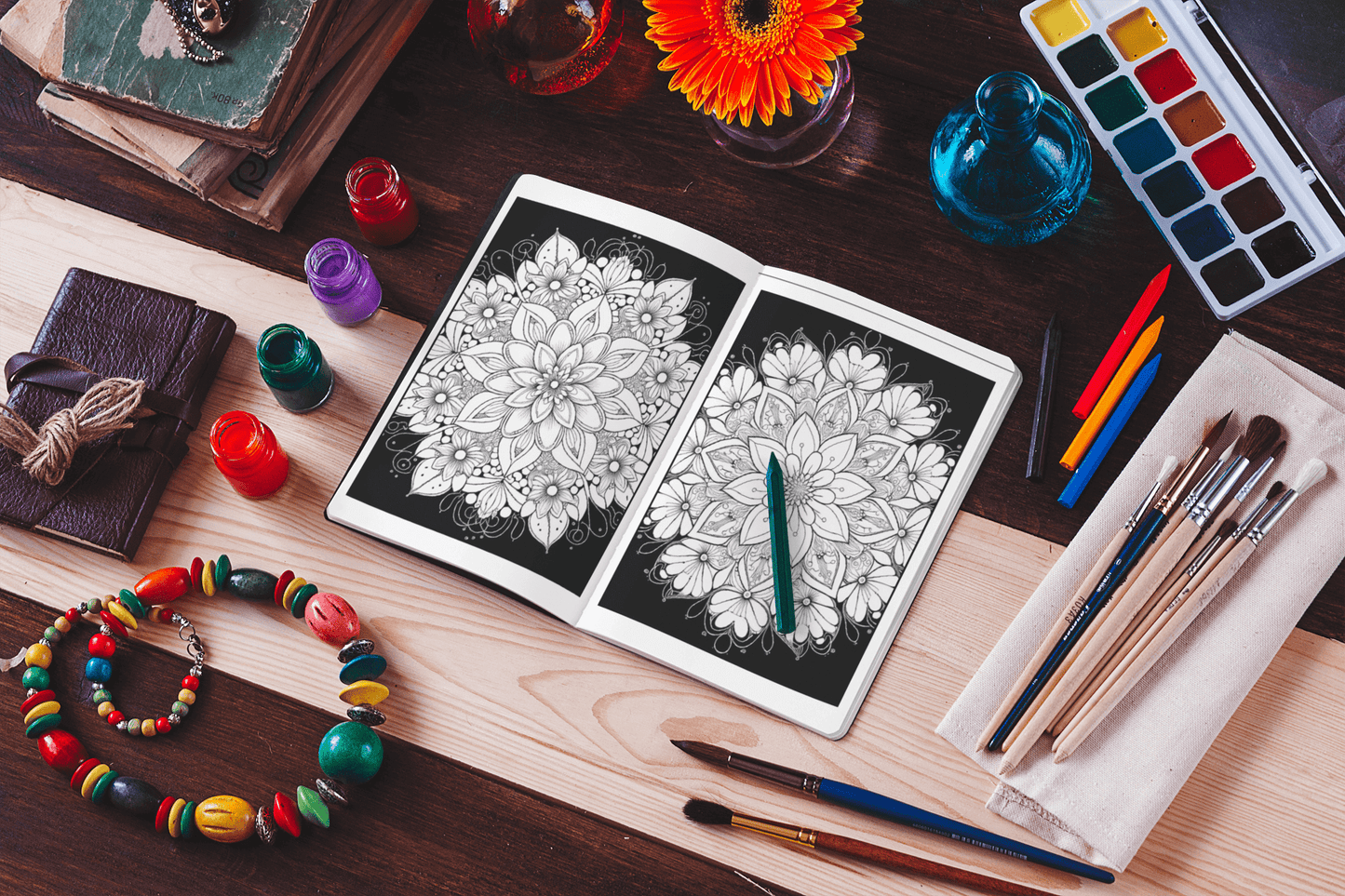 Open mandala coloring book on a wooden table surrounded by art supplies and colorful beads.