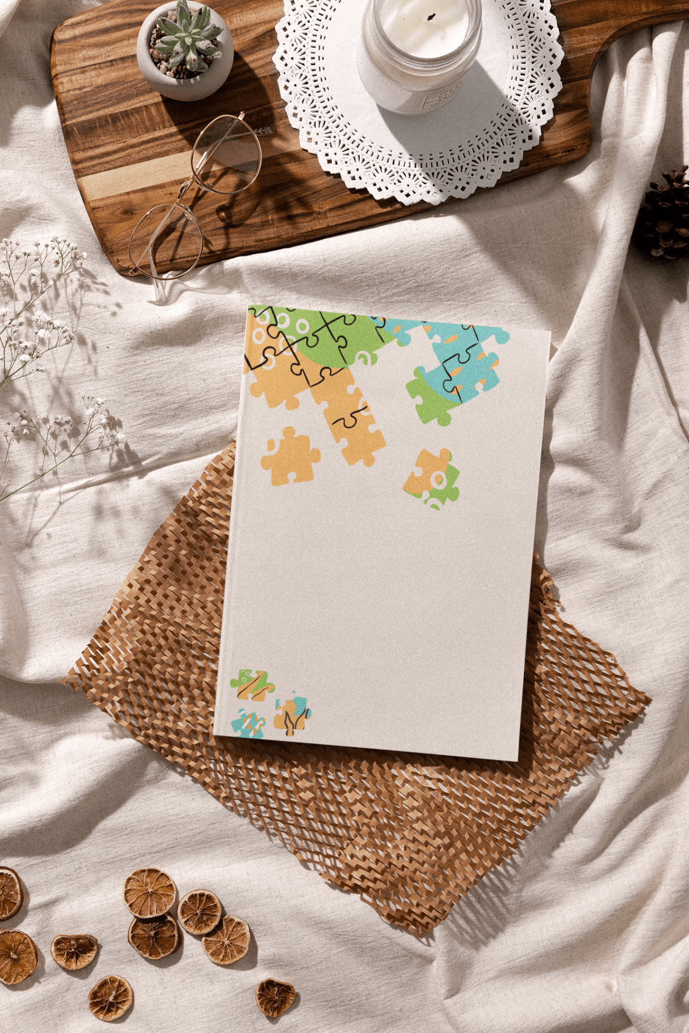 Autism planner journal featuring colorful puzzle piece design, placed on a cozy fabric with decorative items.