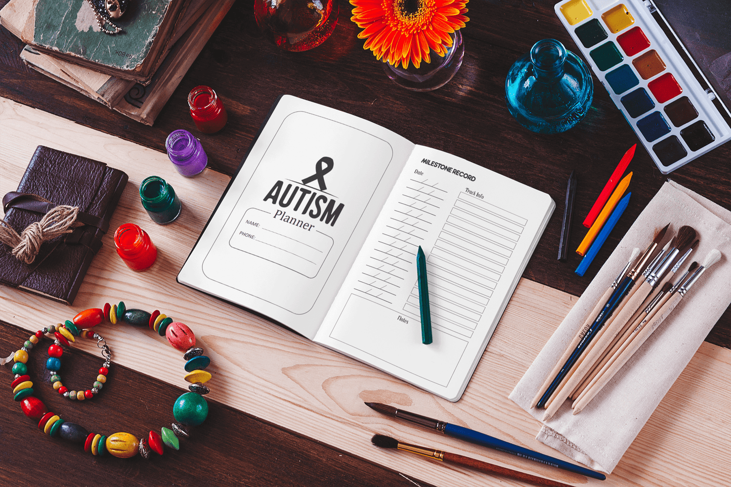 Open Autism Planner Journal on a wooden table with art supplies, showcasing organization for children with autism.