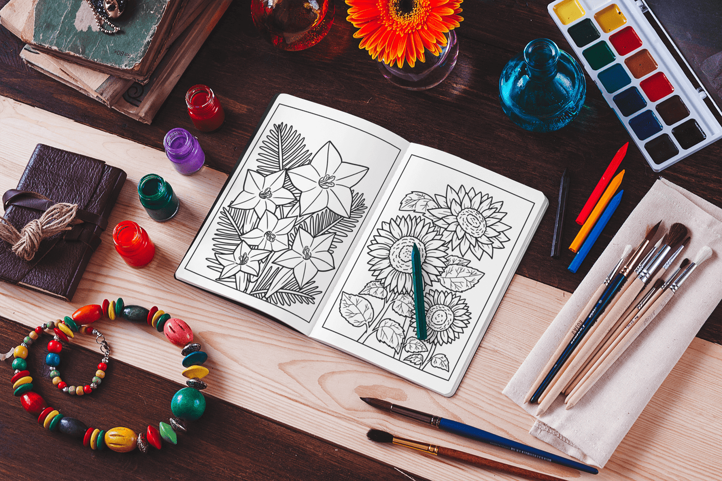 Botanical coloring book open with floral designs, surrounded by art supplies and vibrant flowers.
