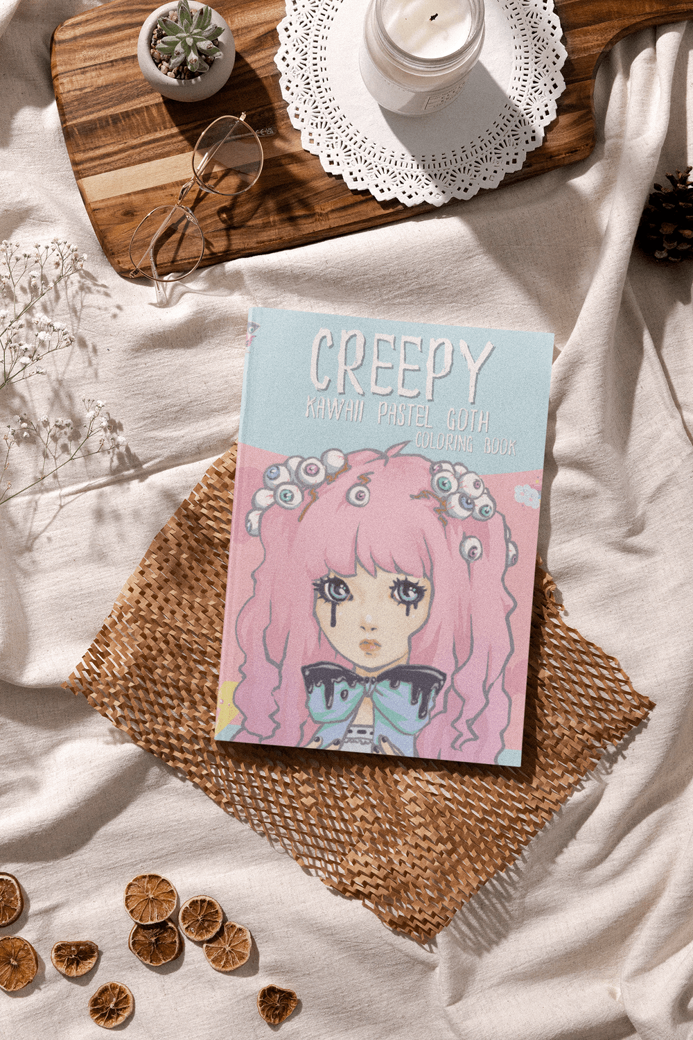 Creepy Kawaii Pastel Goth Coloring Book featuring a pastel-haired character with spooky elements, set on a cozy background.