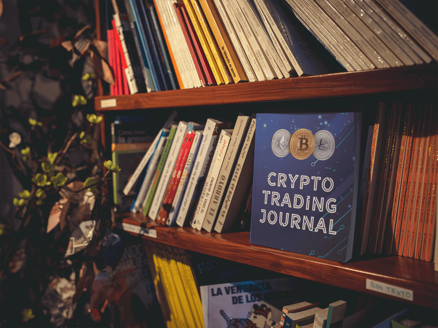Crypto Trading Journal on a bookshelf among other books, ideal for organizing cryptocurrency trades and strategies.