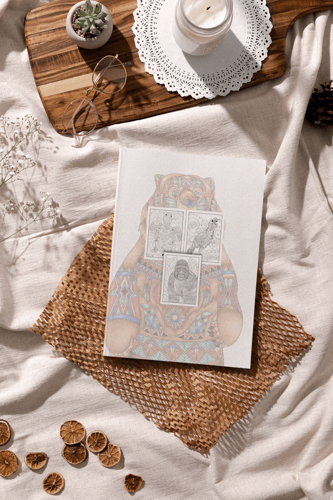 Mandalas & Animals adult coloring book cover featuring a bear design, set on a cozy surface with decorative elements.