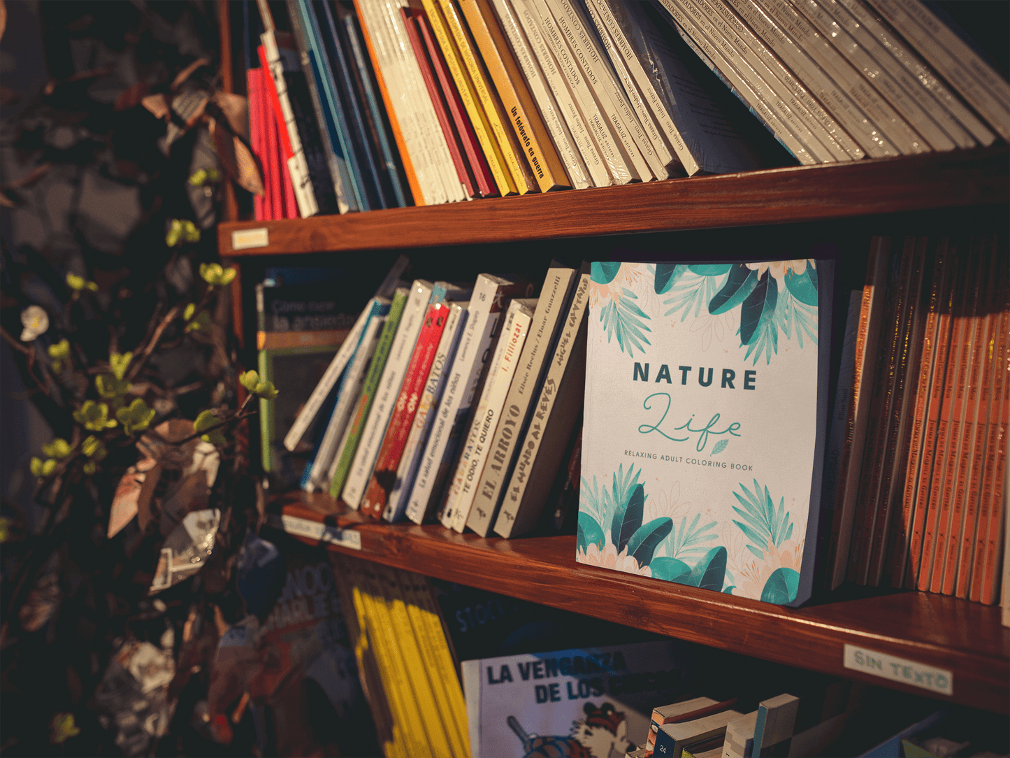 Nature Life Adult Coloring Book displayed on a wooden shelf among various other books.