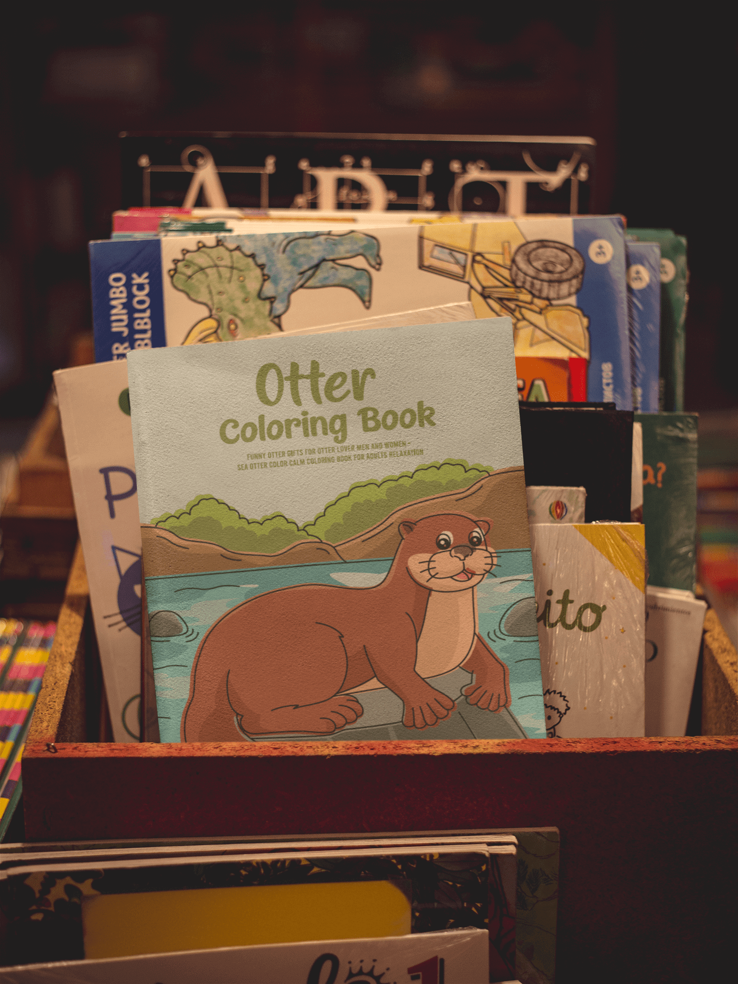 Otter Coloring Book displayed among other coloring books in a wooden box, highlighting stress relief and creativity.