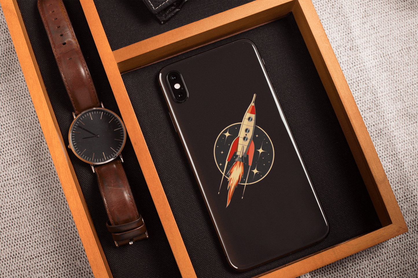 Phone case featuring Atomic Age spacecraft sticker on a wooden tray with a stylish watch.