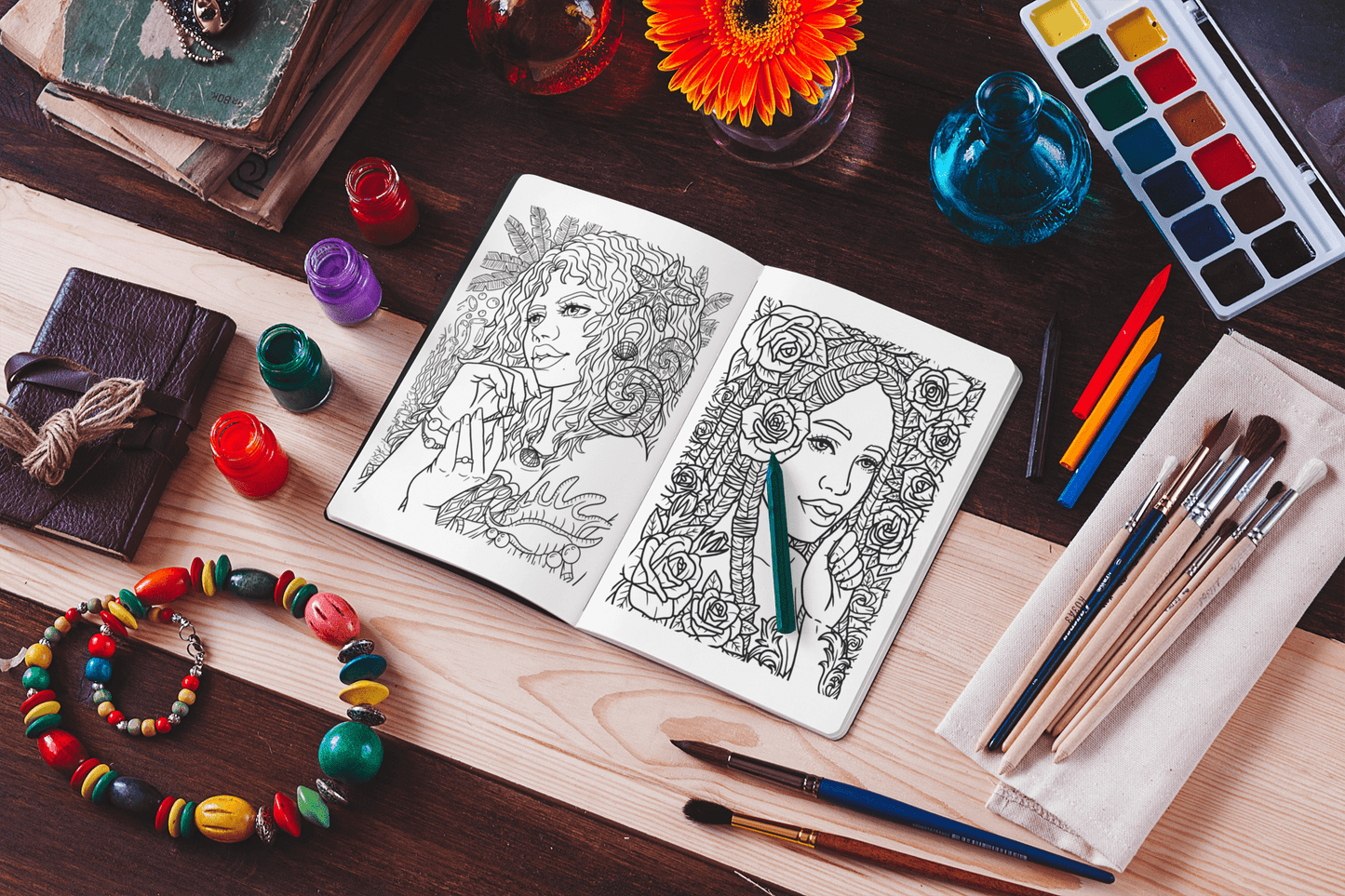 Open coloring book featuring black women illustrations, surrounded by art supplies and vibrant flowers.