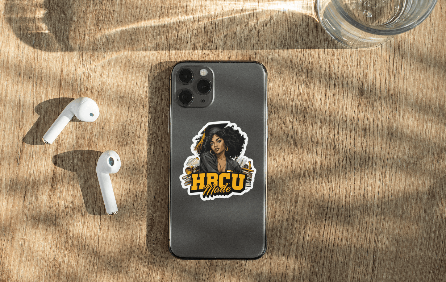 HBCU Made sticker on a smartphone with AirPods, showcasing vibrant design and personalization.