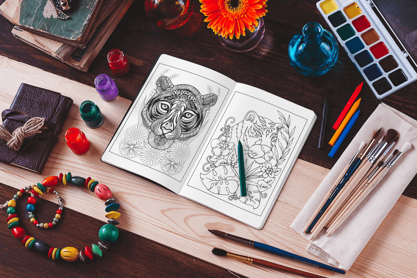 Open tiger coloring book on a wooden table with art supplies, vibrant paints, and a colorful flower centerpiece.
