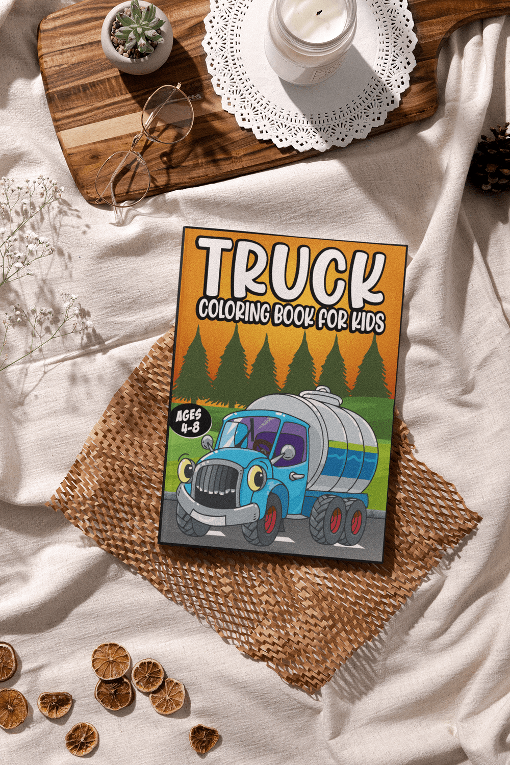 Truck coloring book for kids ages 4-8 with a cartoon truck cover, placed on a decorative table setting.