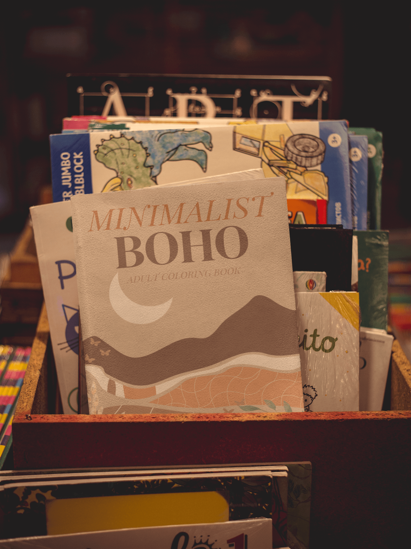 Cover of Minimalist Boho Adult Coloring Book displayed among other coloring books in a cozy setting.